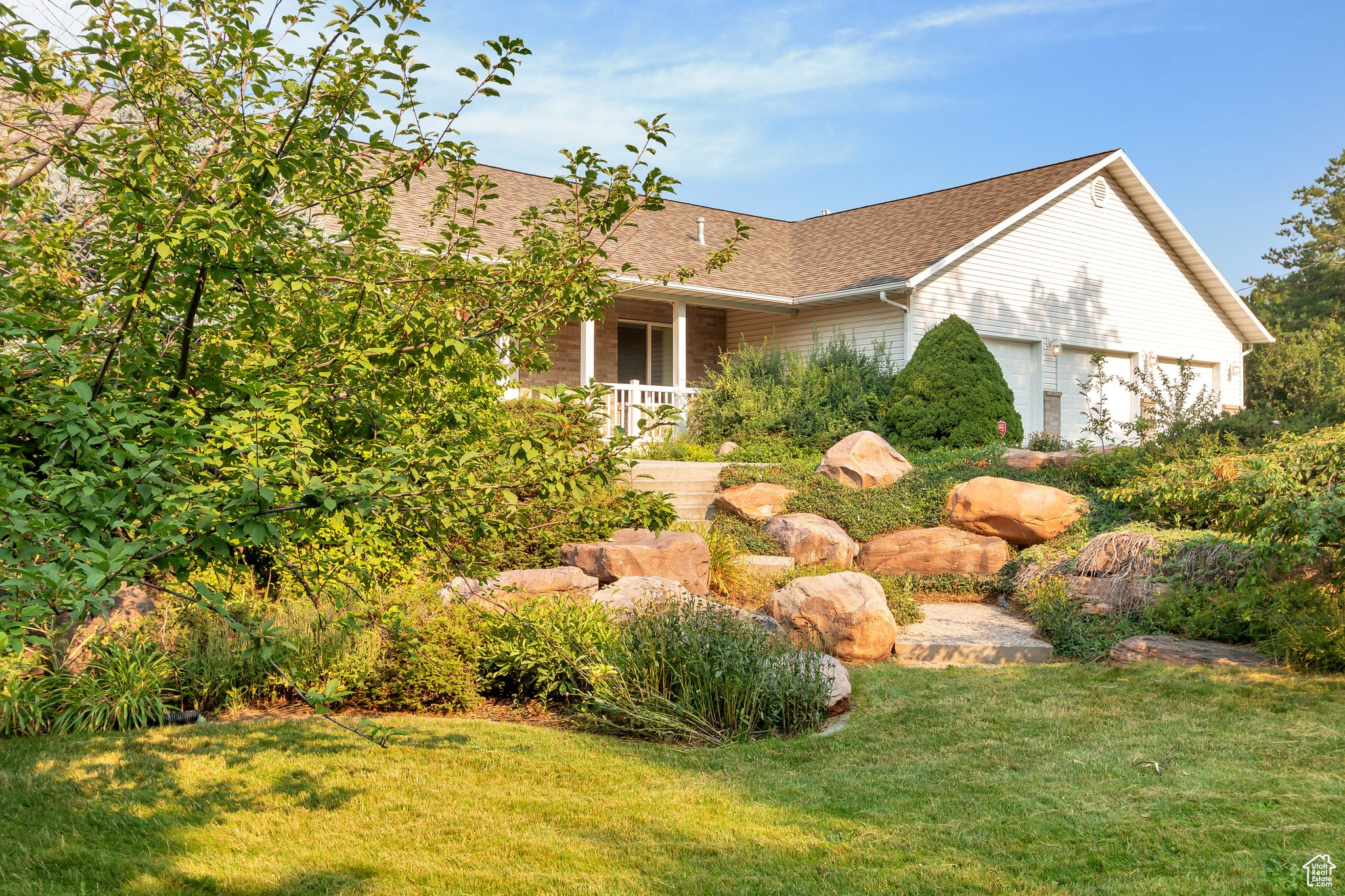 View of front of home featuring a front lawn, a porch, and a garage