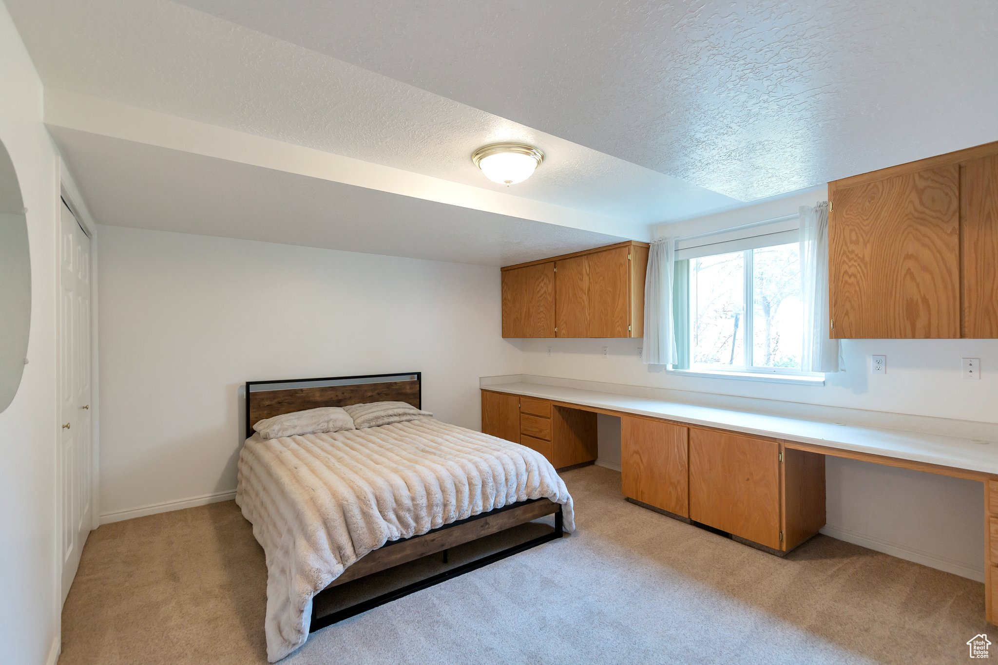 Bedroom with built in desk and light colored carpet