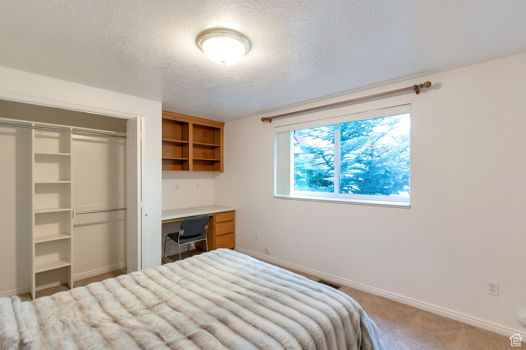 Carpeted bedroom featuring a textured ceiling and a closet