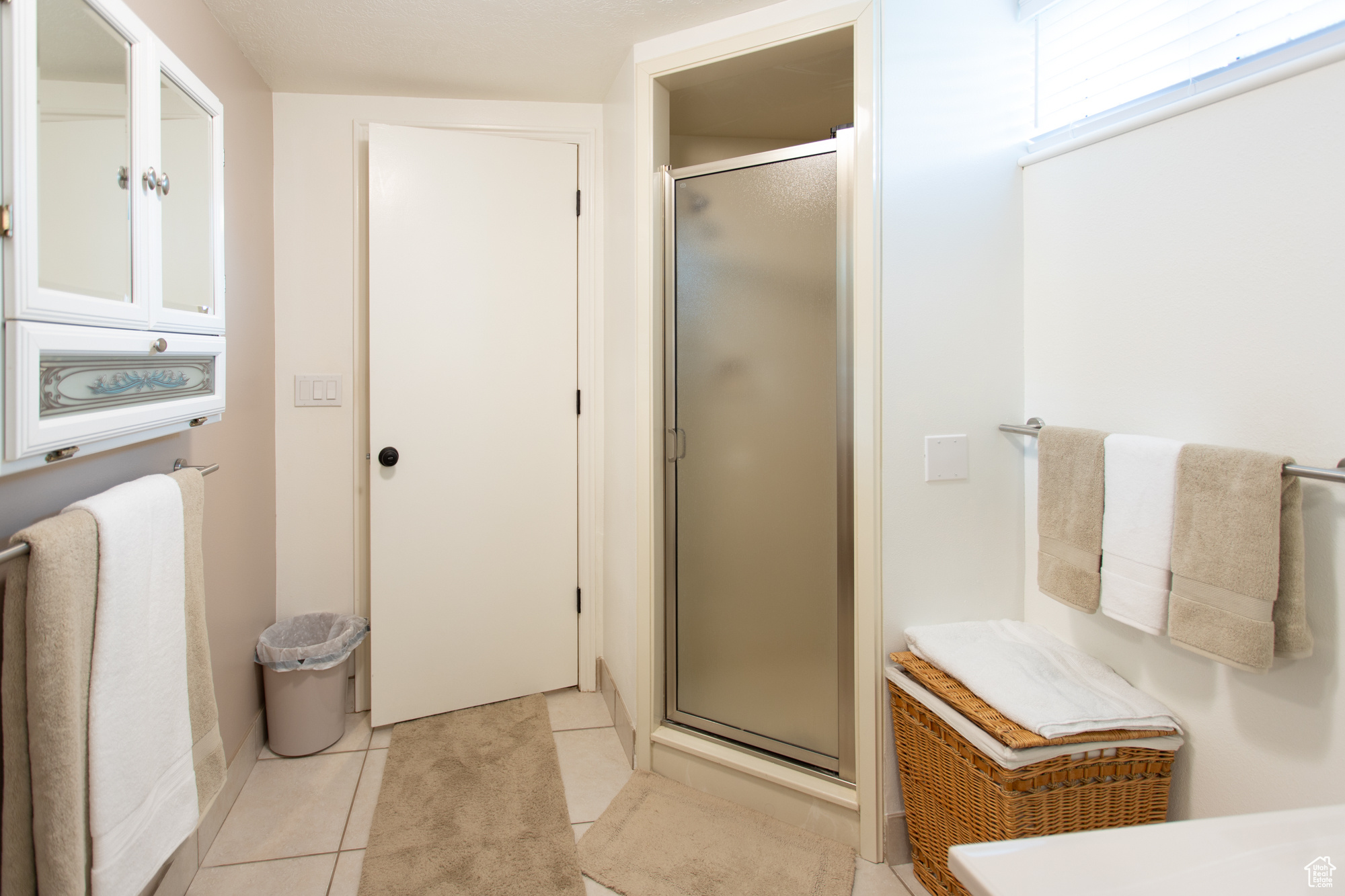 Bathroom with tile patterned floors and a shower with door