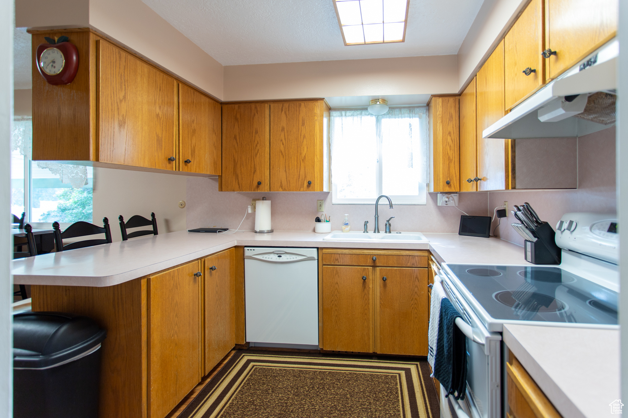 Kitchen with kitchen peninsula, white appliances, and sink