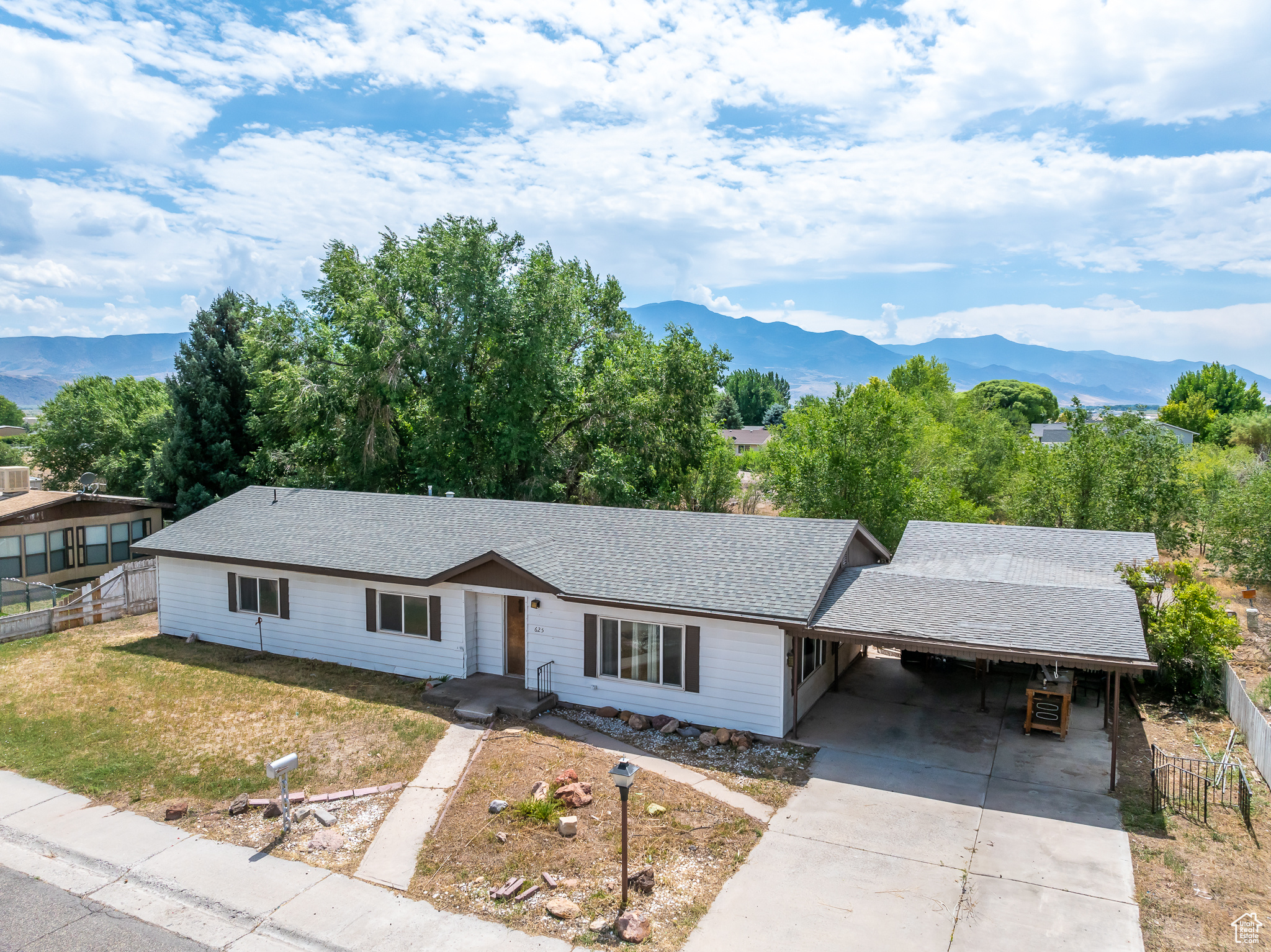 Ranch-style home with a front lawn, a mountain view, and a carport