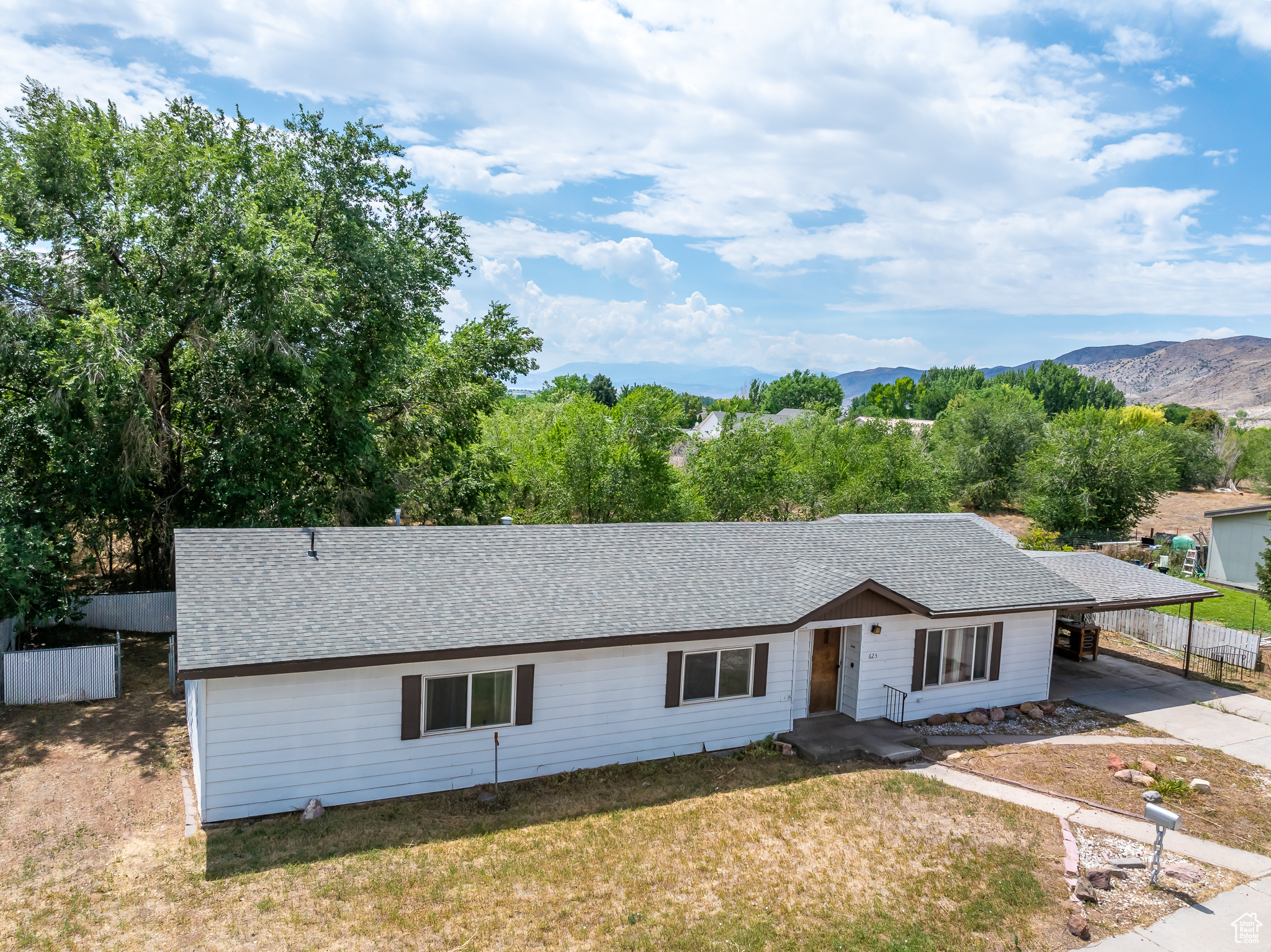 Ranch-style home with a carport, a mountain view, and a front lawn