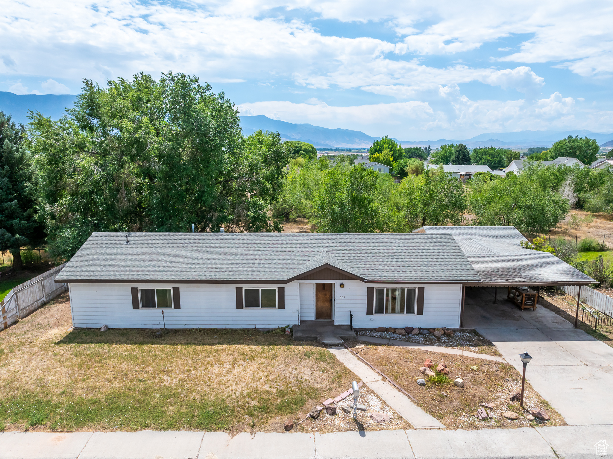 Ranch-style home featuring a mountain view, a front yard, and a carport