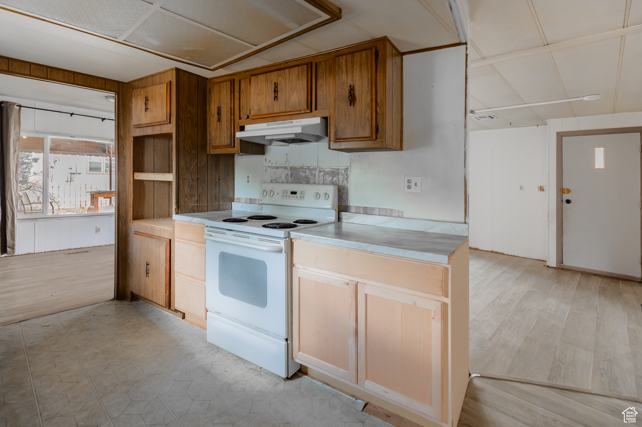 Kitchen with backsplash, white range with electric stovetop, and light hardwood / wood-style floors