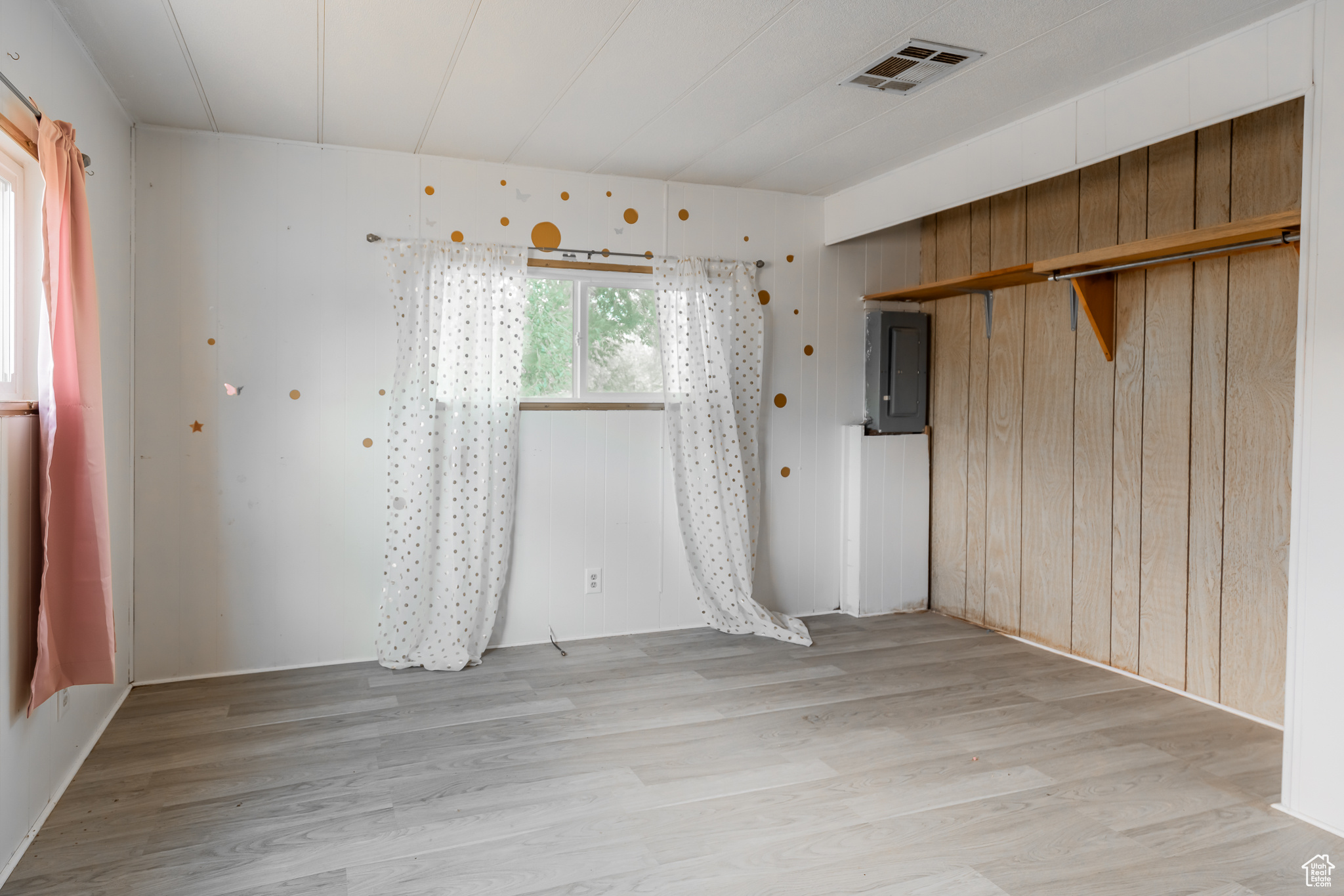 Empty room featuring light wood-type flooring and electric panel