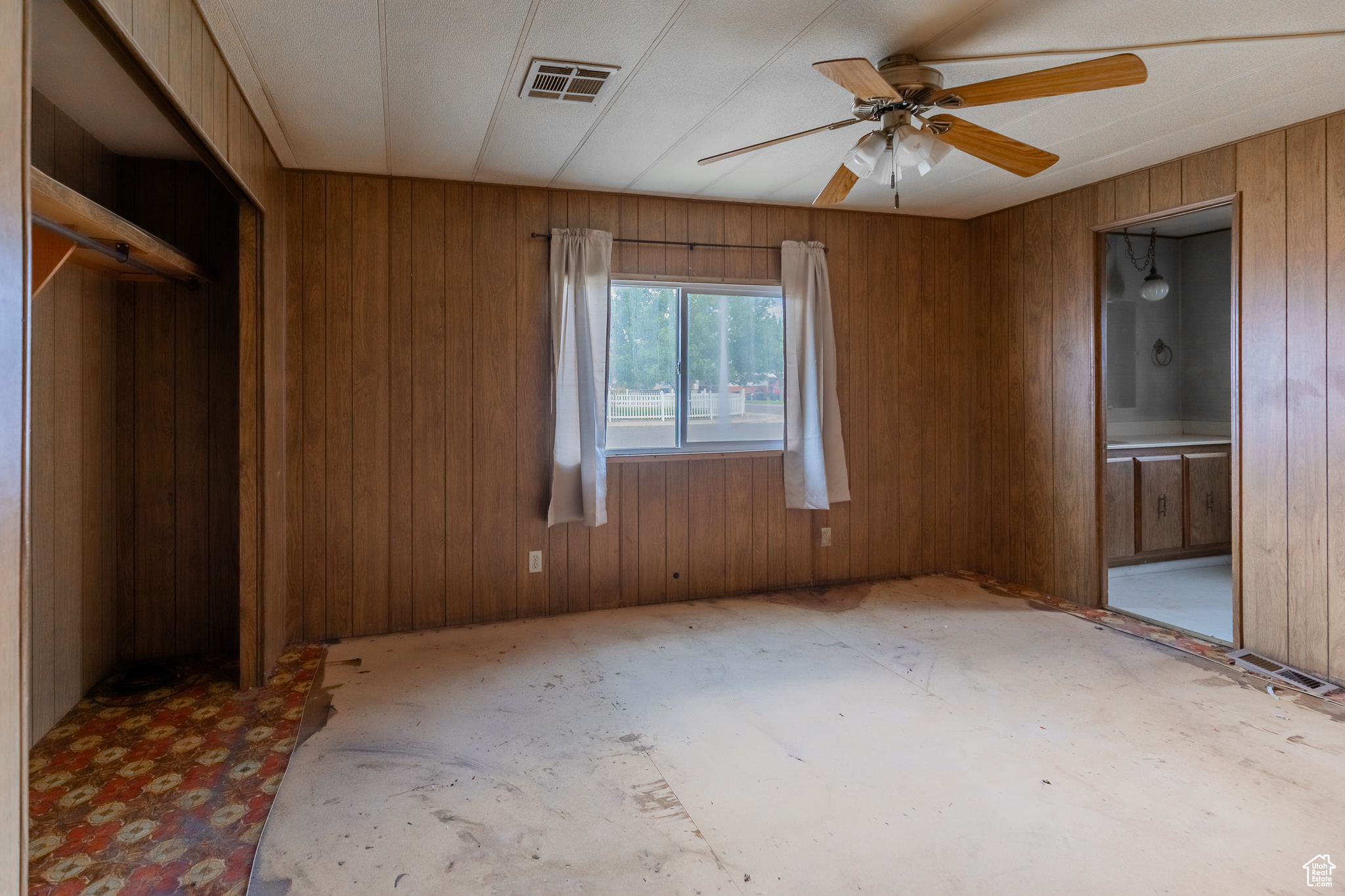 Unfurnished room with ceiling fan and wooden walls