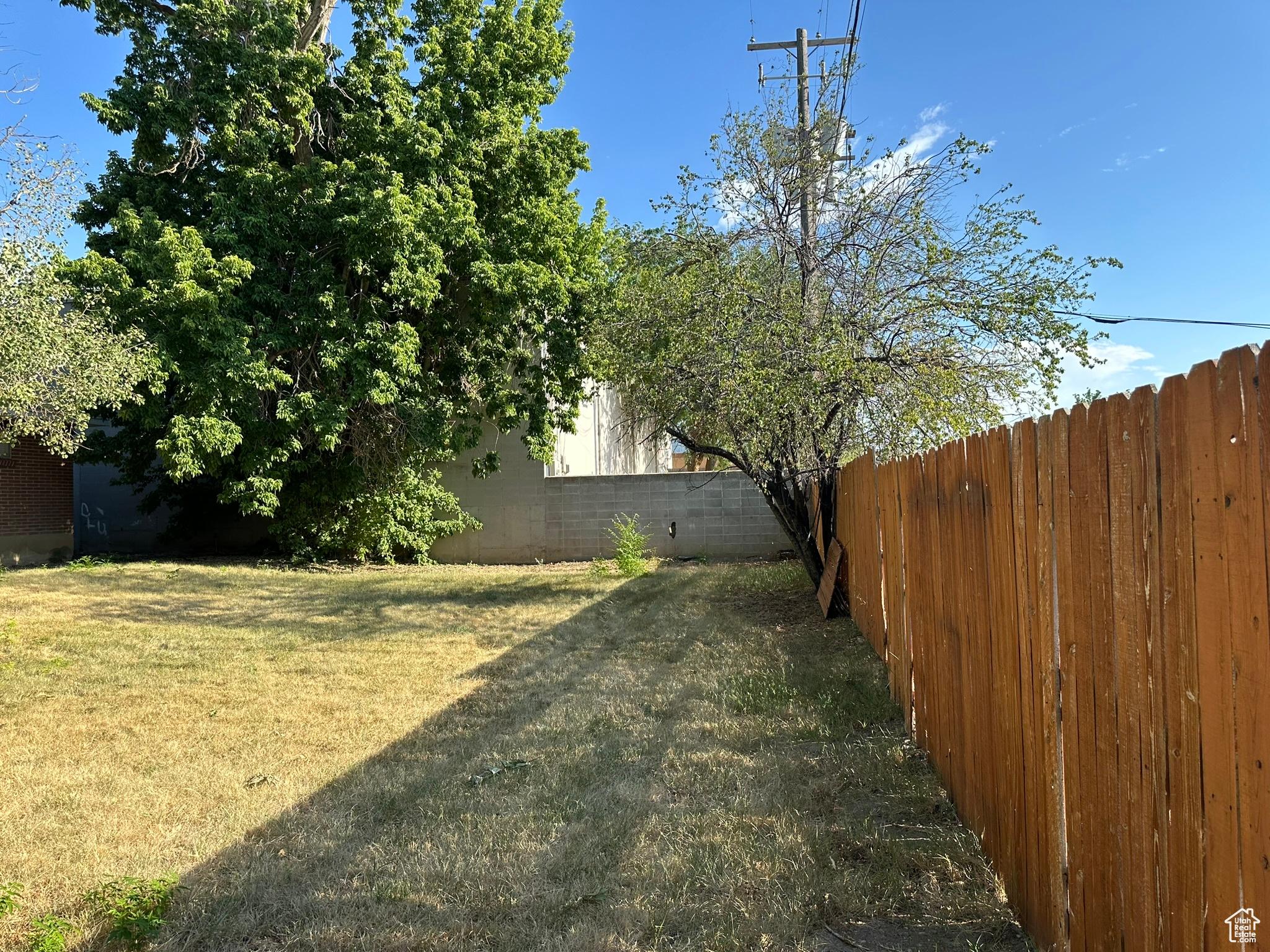 View of backyard featuring fully fenced, mature trees, fully automated sprinkling system