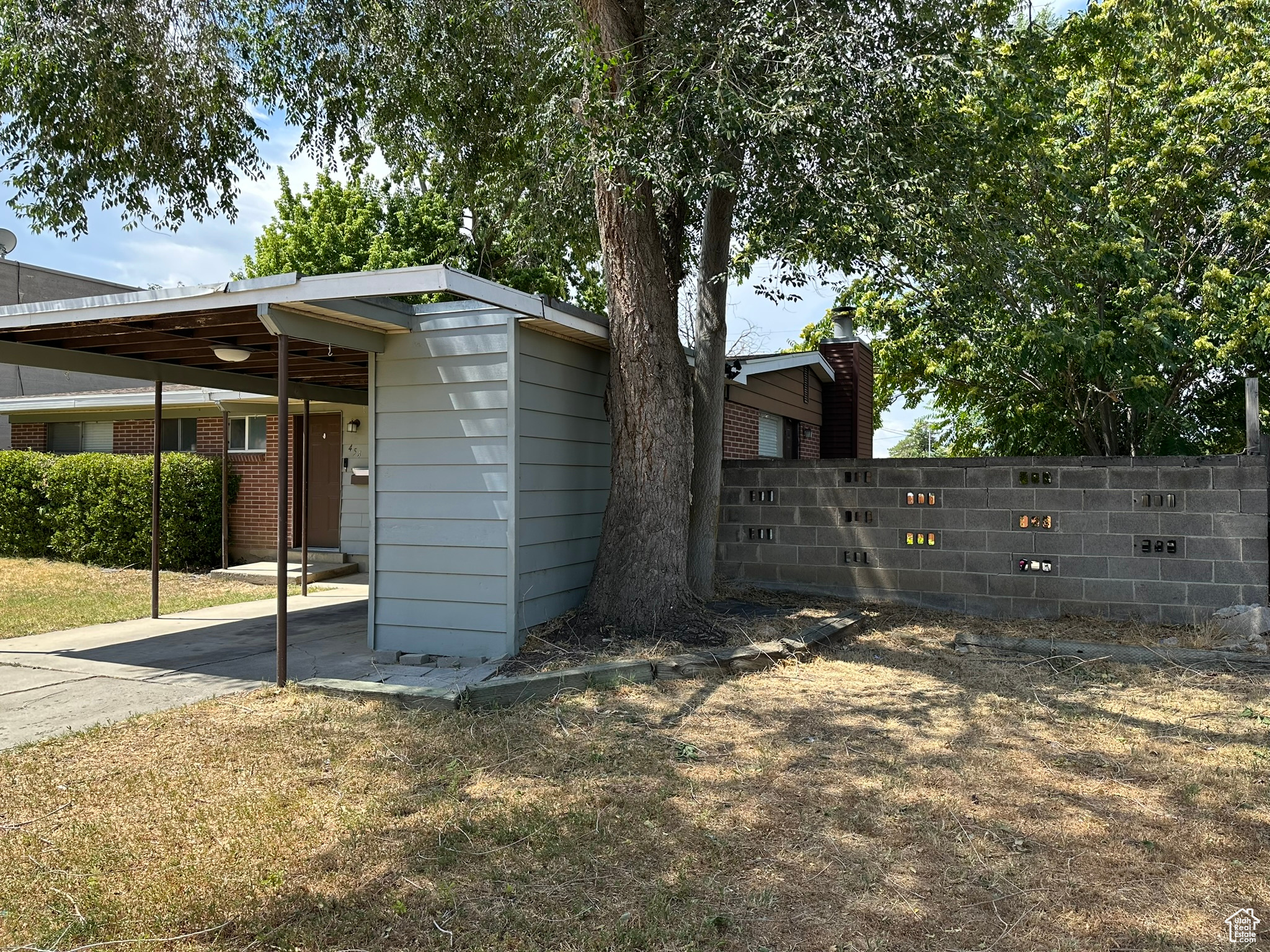 View of side of property with mature trees and storage shed