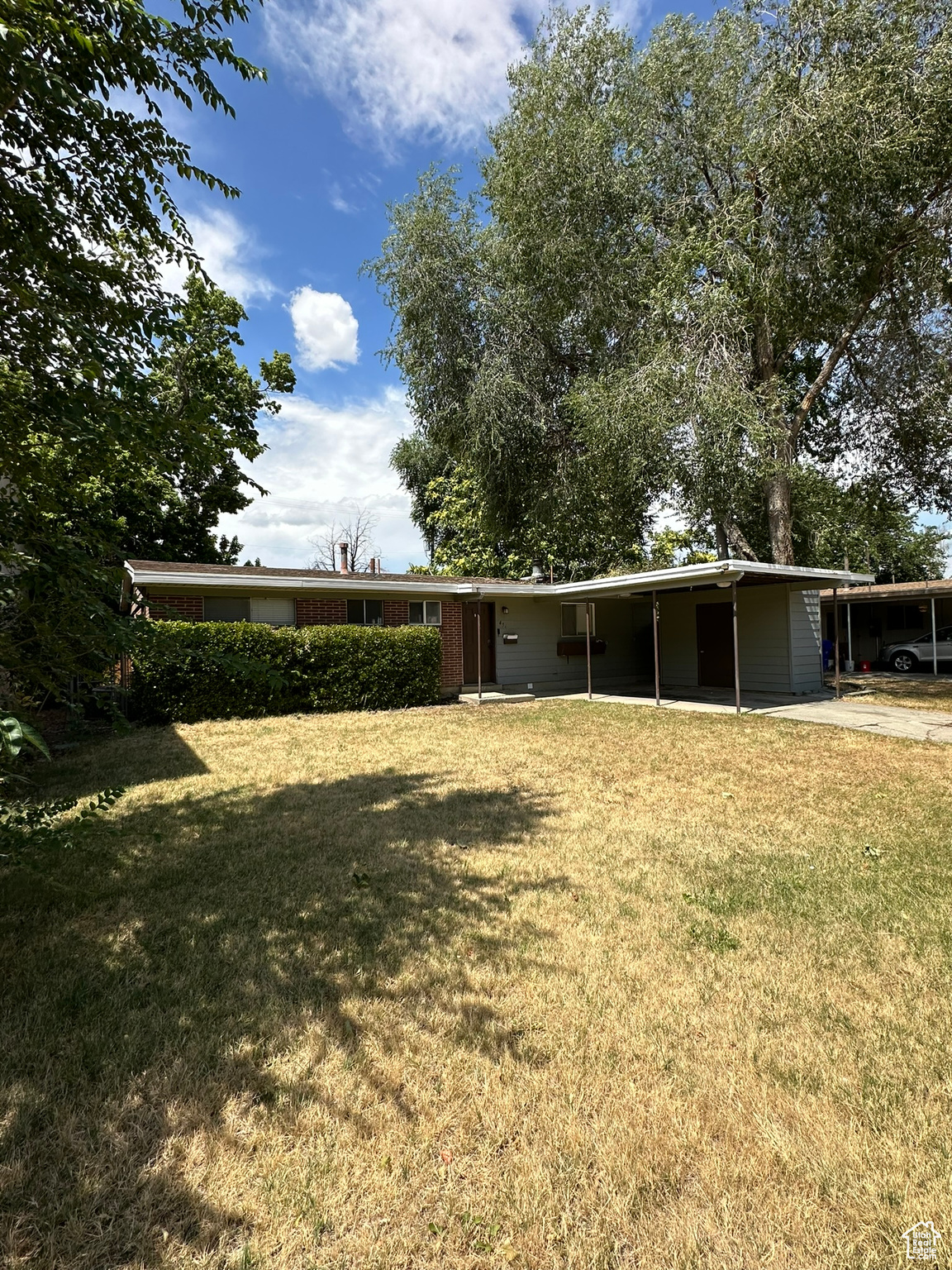 View of the front of hte house, yard with a carport and attached storage shed