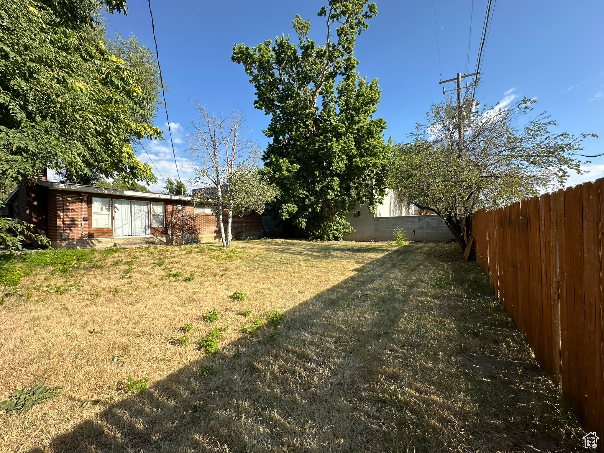 View of backyard featuring fully fenced, mature trees, fully automated sprinkling system