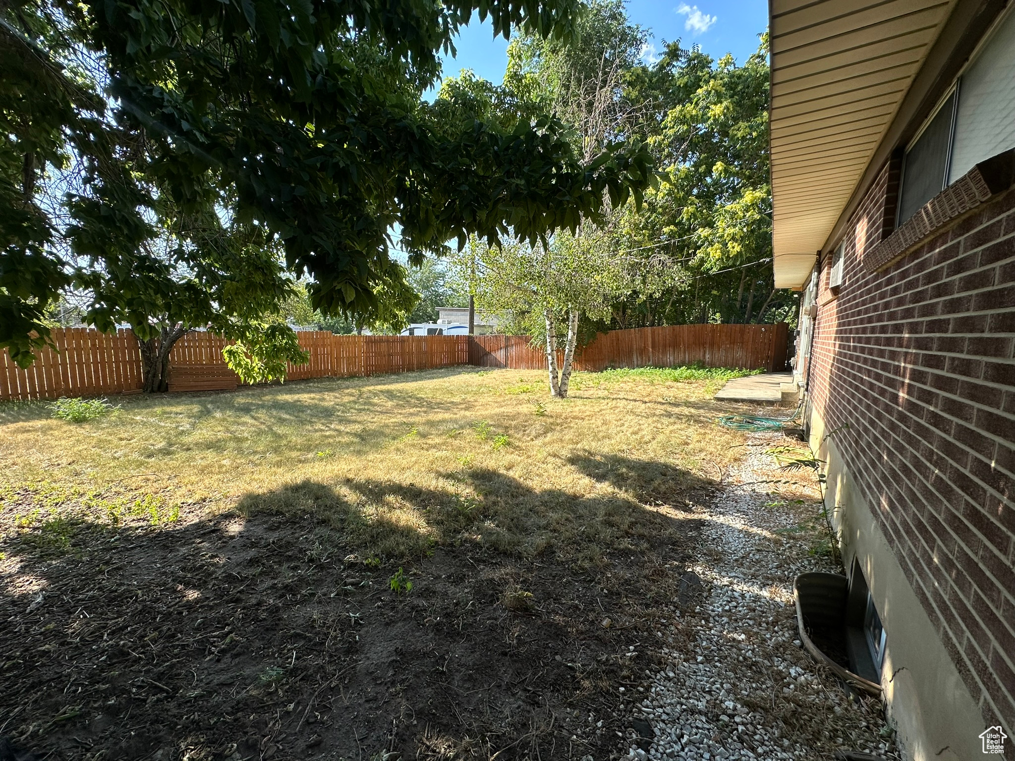 View of backyard featuring fully fenced, mature trees, fully automated sprinkling system