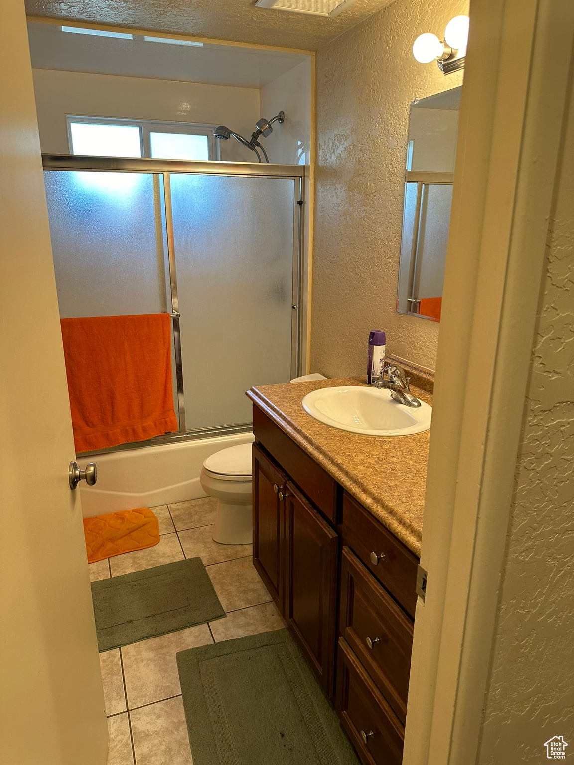 Main full bathroom with tile floor, vanity, toilet, and shower / bath combination with glass door