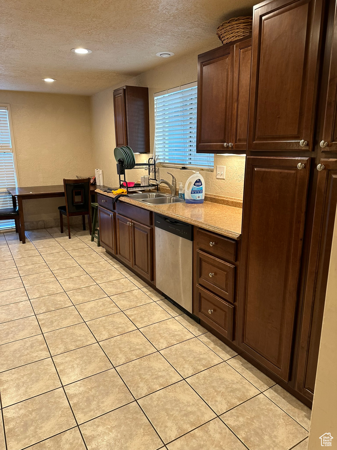 Kitchen with dishwasher, sink, a textured ceiling, and light tile patterned floors