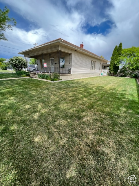 Rear view of property featuring a yard and covered porch