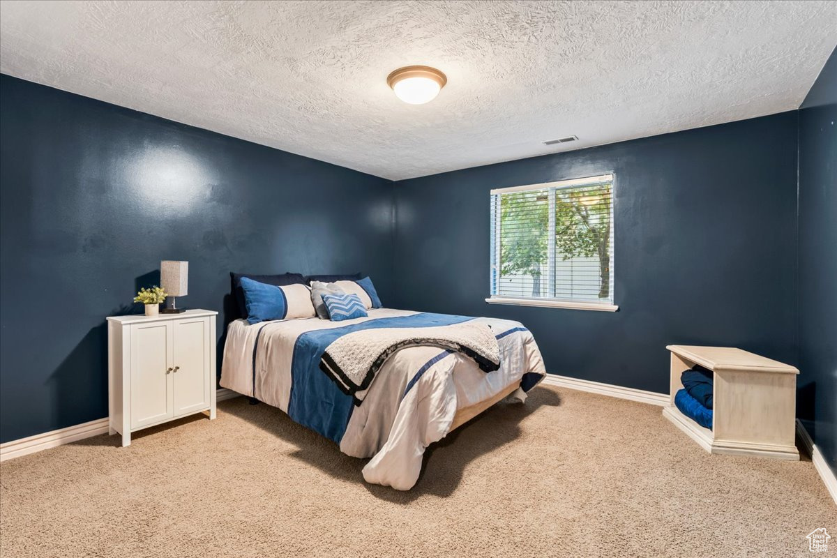 Bedroom featuring a textured ceiling and light carpet