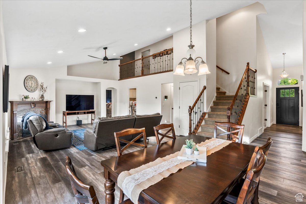 Dining area featuring high vaulted ceiling, ceiling fan with notable chandelier, and dark hardwood / wood-style floors