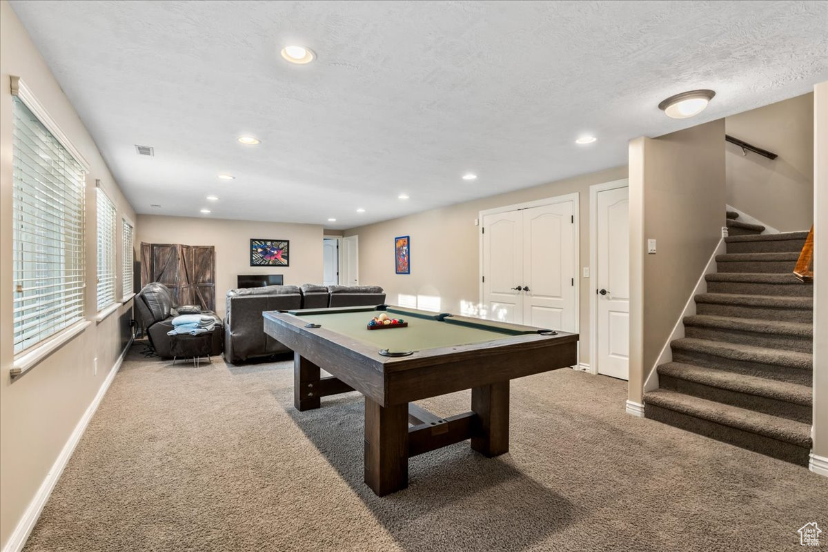 Playroom featuring pool table, a textured ceiling, and light colored carpet