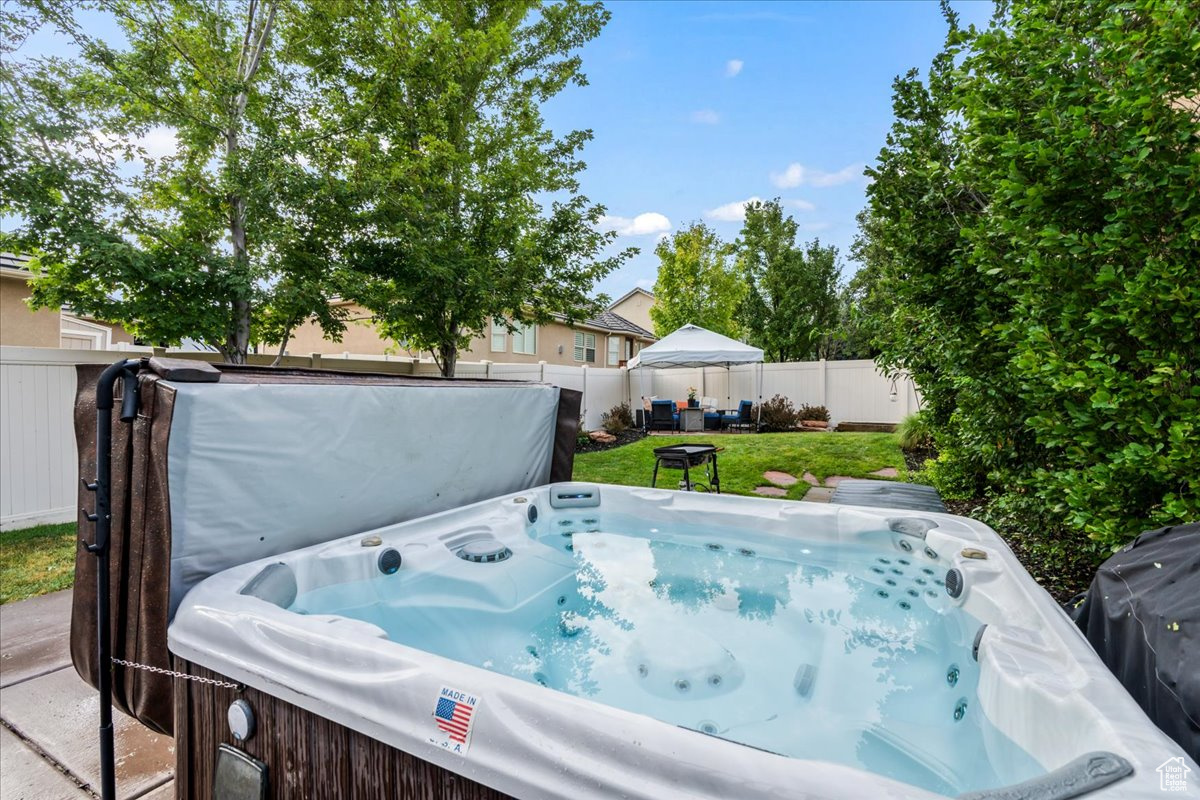 View of swimming pool with a hot tub and a yard