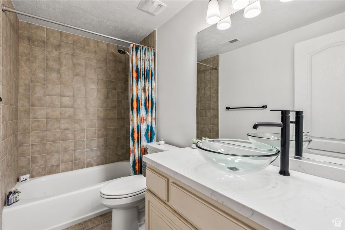 Full bathroom featuring toilet, shower / bath combination with curtain, vanity, and tile patterned flooring