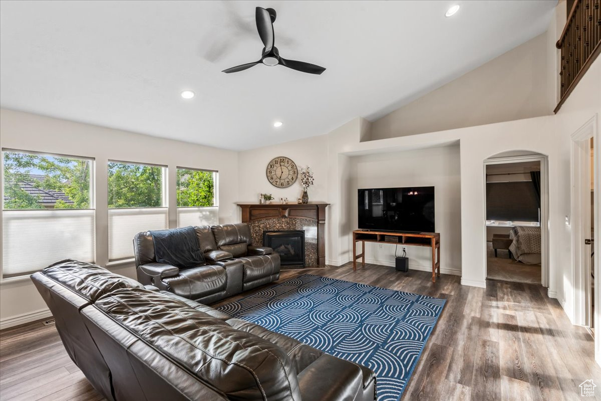 Living room with ceiling fan, wood-type flooring, and high vaulted ceiling