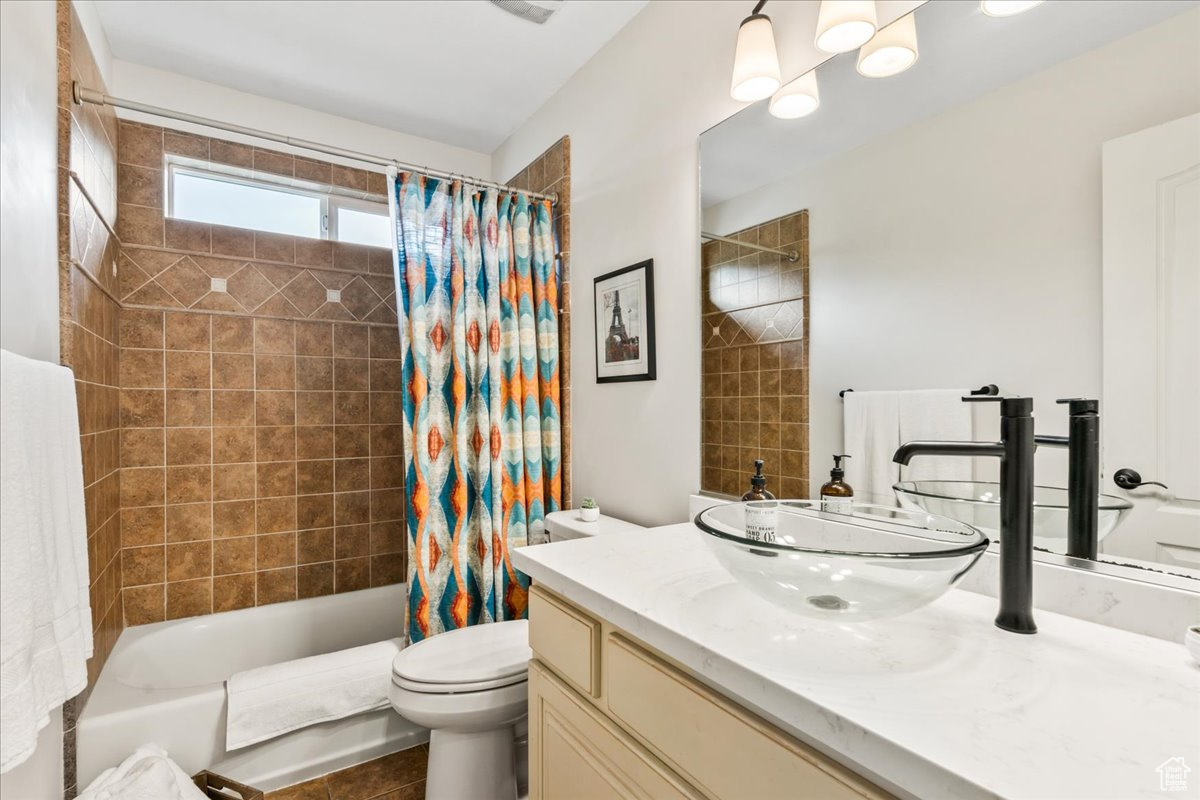 Full bathroom with shower / tub combo, vanity, tile patterned floors, and toilet