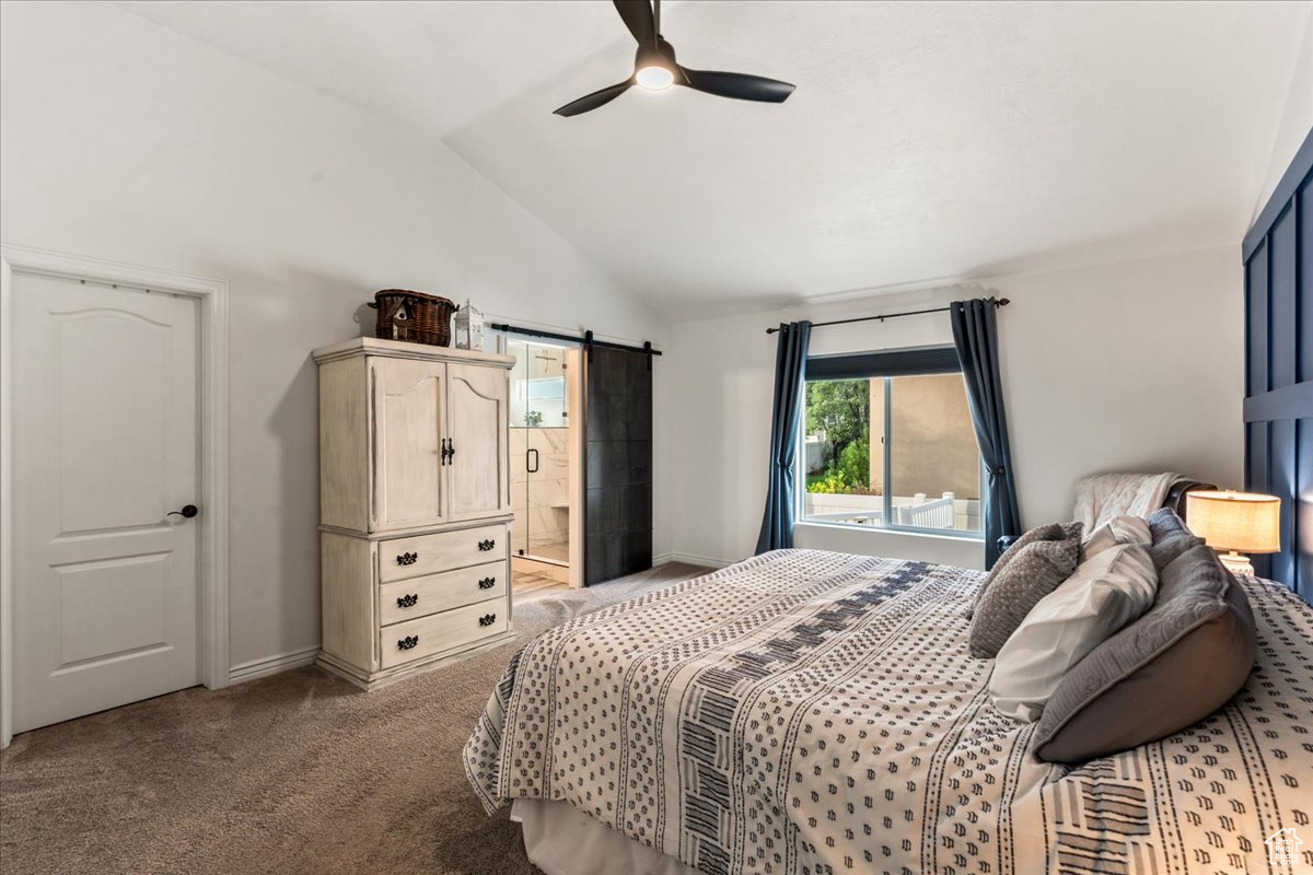 Bedroom featuring lofted ceiling, ceiling fan, a barn door, ensuite bath, and carpet