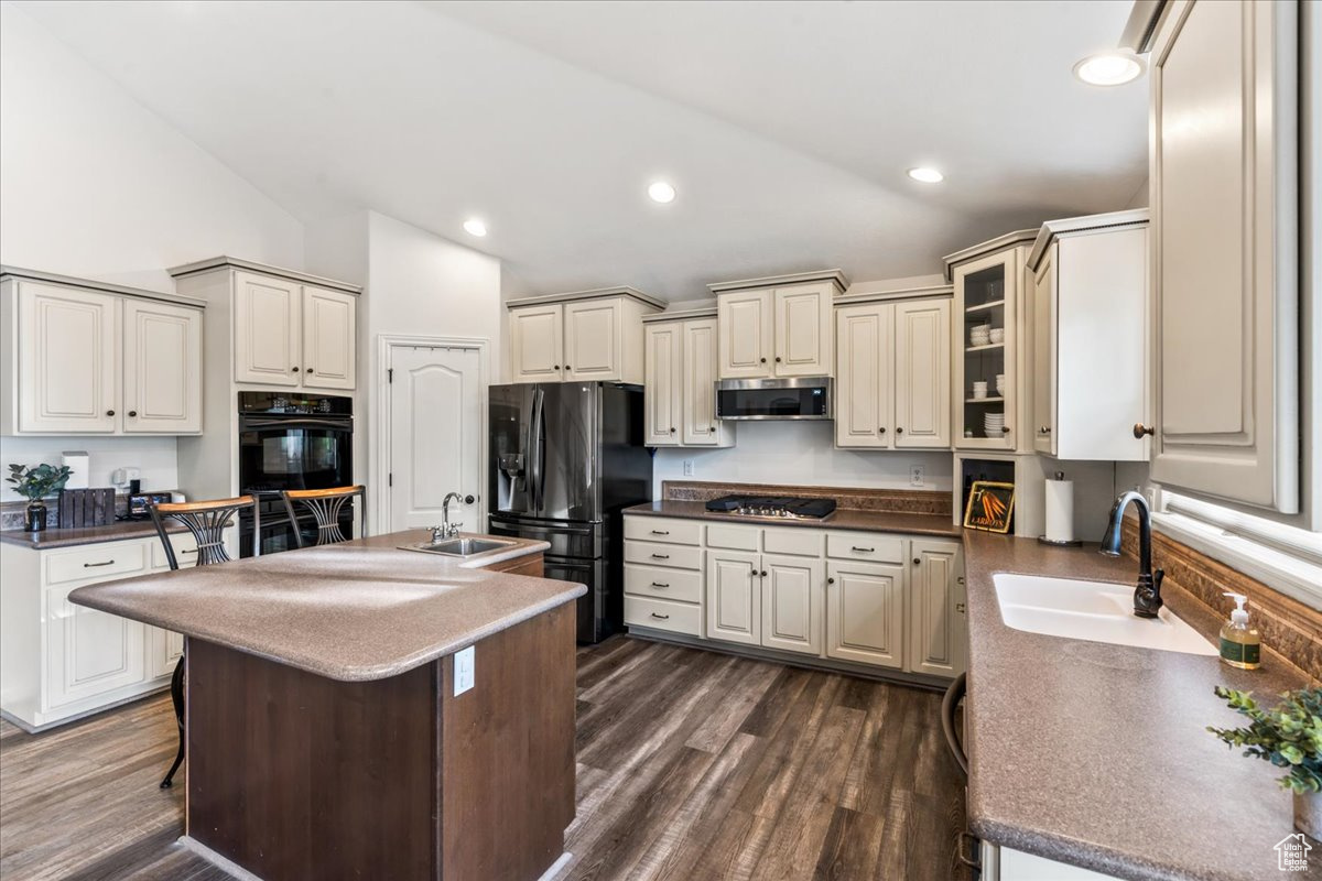 Kitchen with sink, dark wood-type flooring, stainless steel appliances, and a kitchen breakfast bar