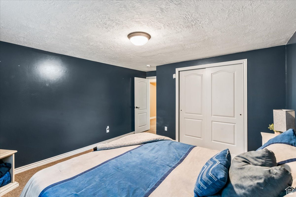 Bedroom featuring a textured ceiling, a closet, and carpet