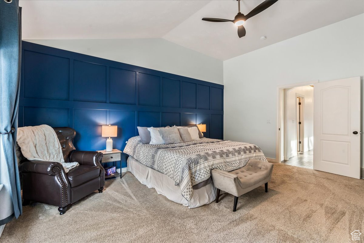 Carpeted bedroom featuring ceiling fan and lofted ceiling