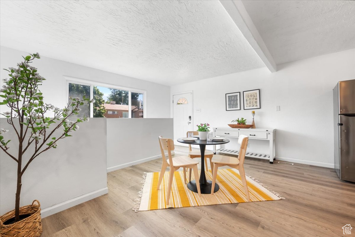 Dining area with light hardwood / wood-style flooring and a textured ceiling