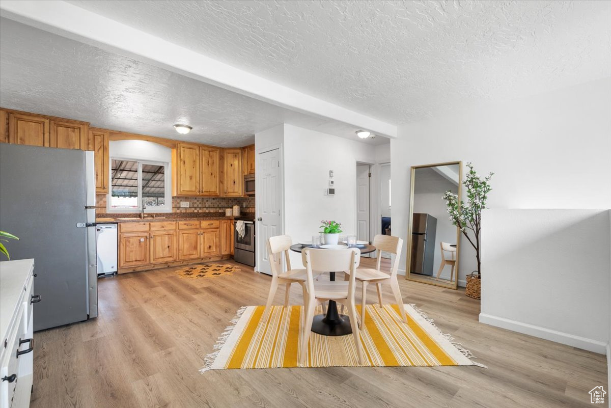 Kitchen featuring range, light hardwood / wood-style flooring, white dishwasher, and stainless steel refrigerator