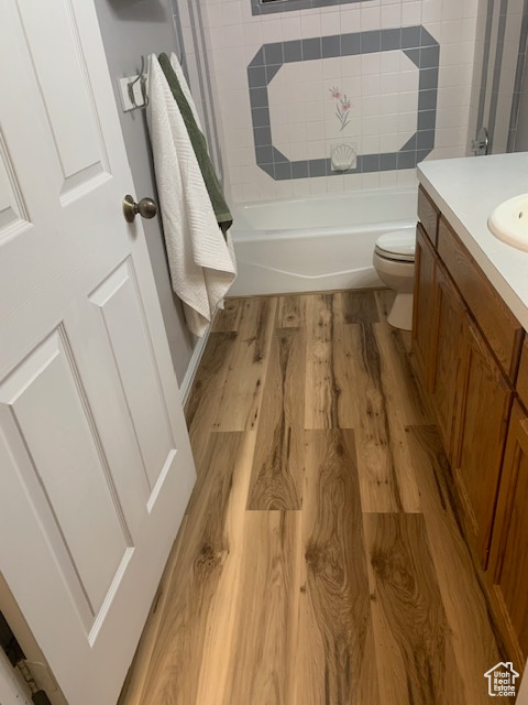 Full bathroom featuring hardwood / wood-style flooring, vanity, toilet, and bathing tub / shower combination