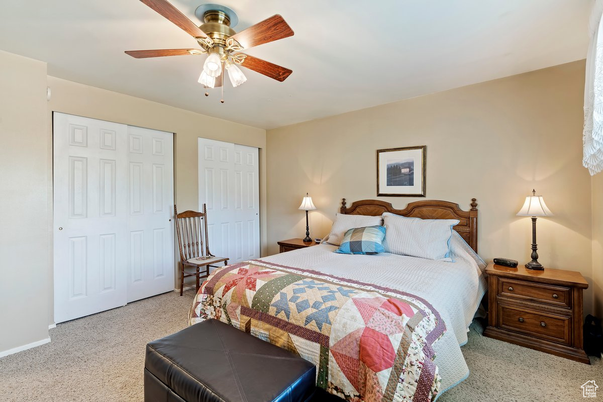 Carpeted bedroom with a closet and ceiling fan