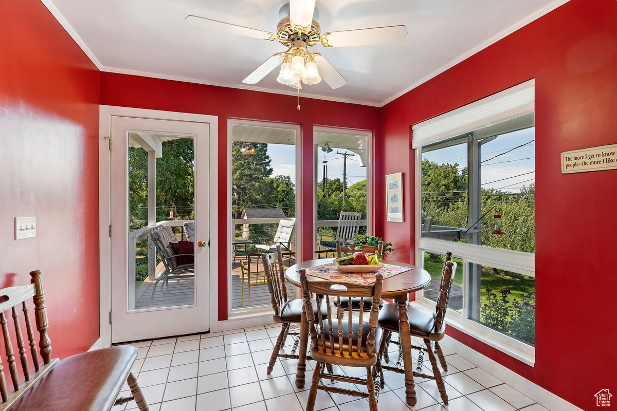 Tiled dining room featuring a wealth of natural light, ceiling fan, and crown molding