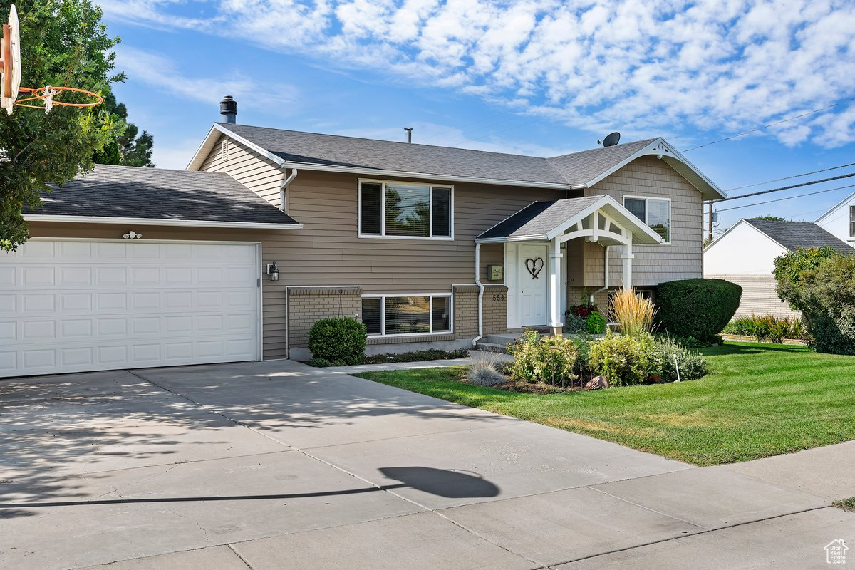 Bi-level home featuring a garage and a front yard