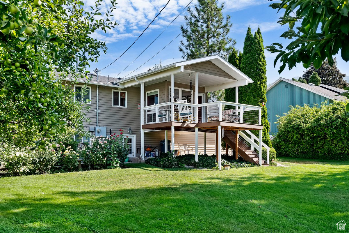 Rear view of house with a yard and a wooden deck