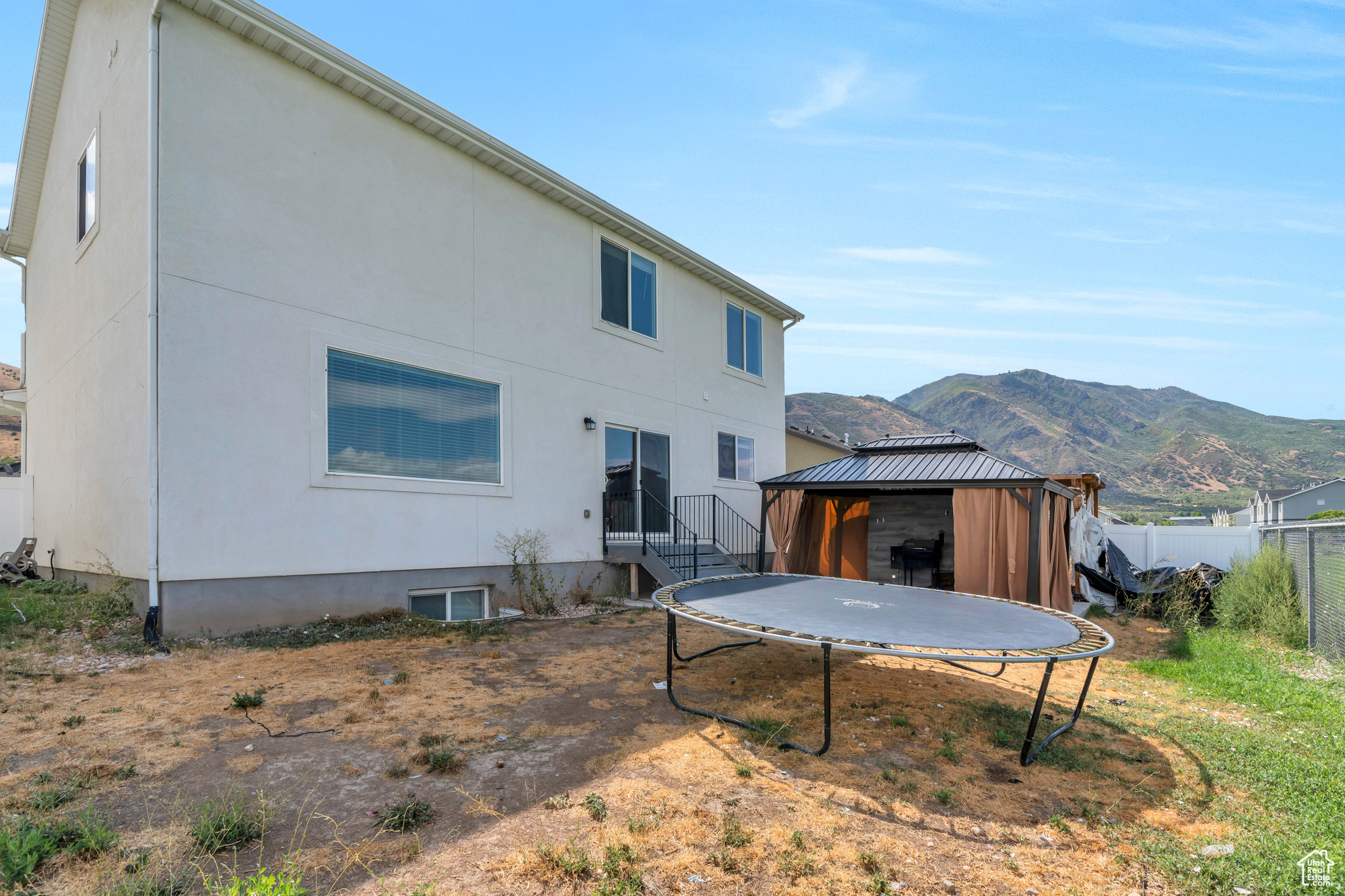 Rear view of property featuring a trampoline, a gazebo, and a mountain view