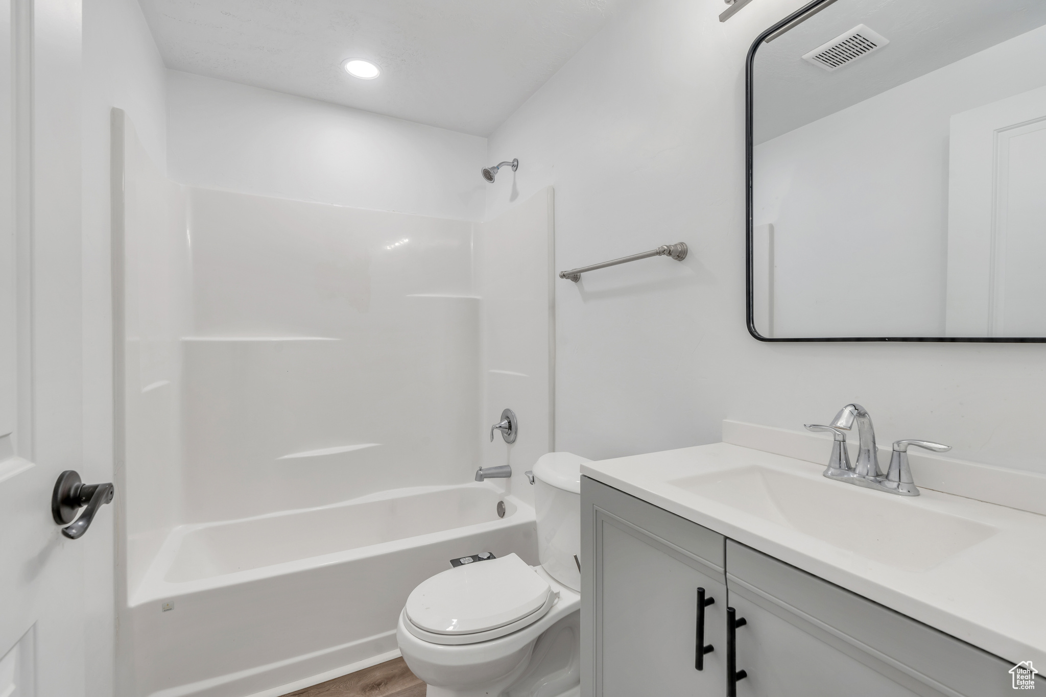 Full bathroom with hardwood / wood-style floors, shower / bathtub combination, toilet, and vanity