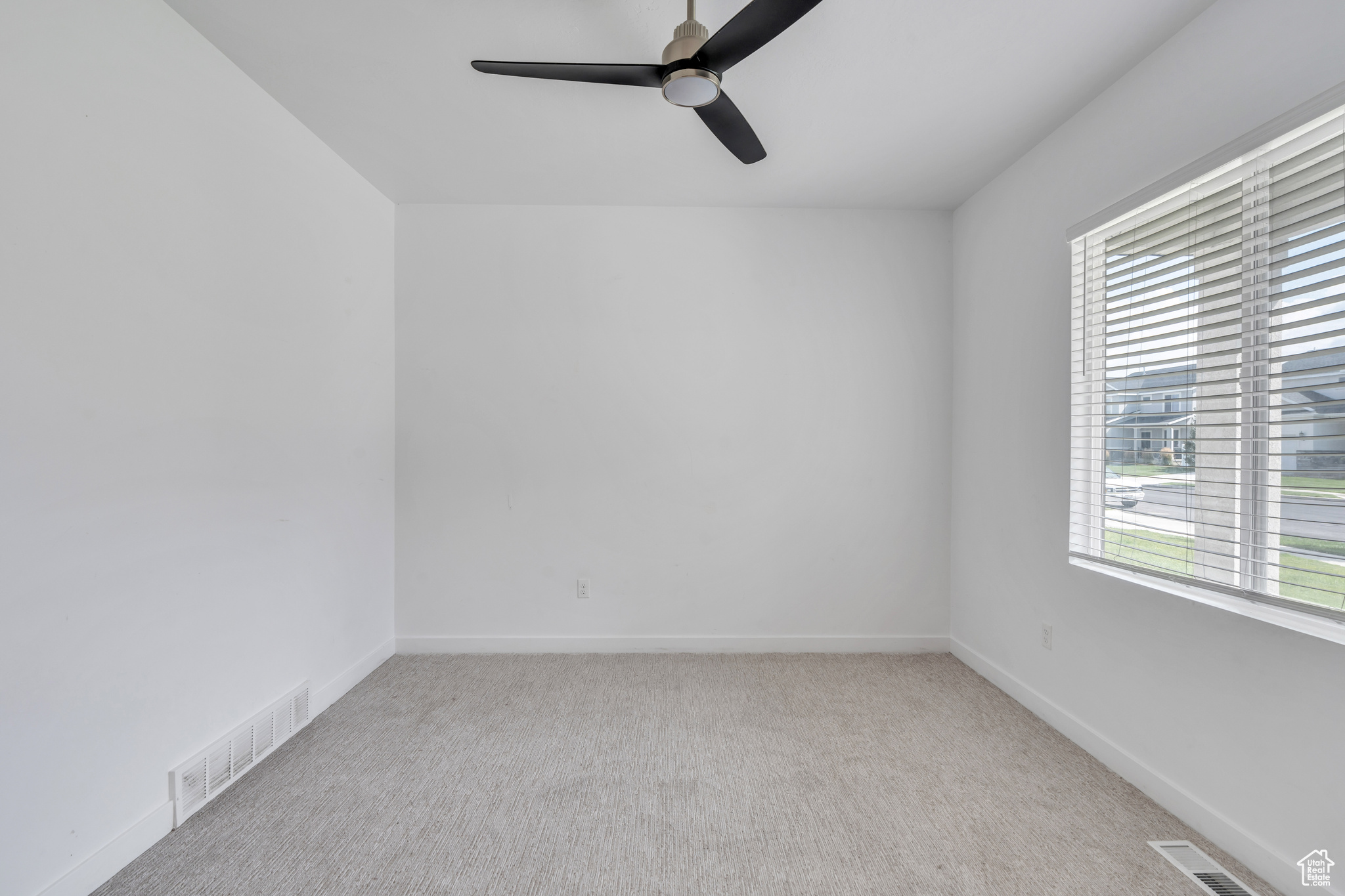 Unfurnished room featuring a wealth of natural light, light carpet, and ceiling fan