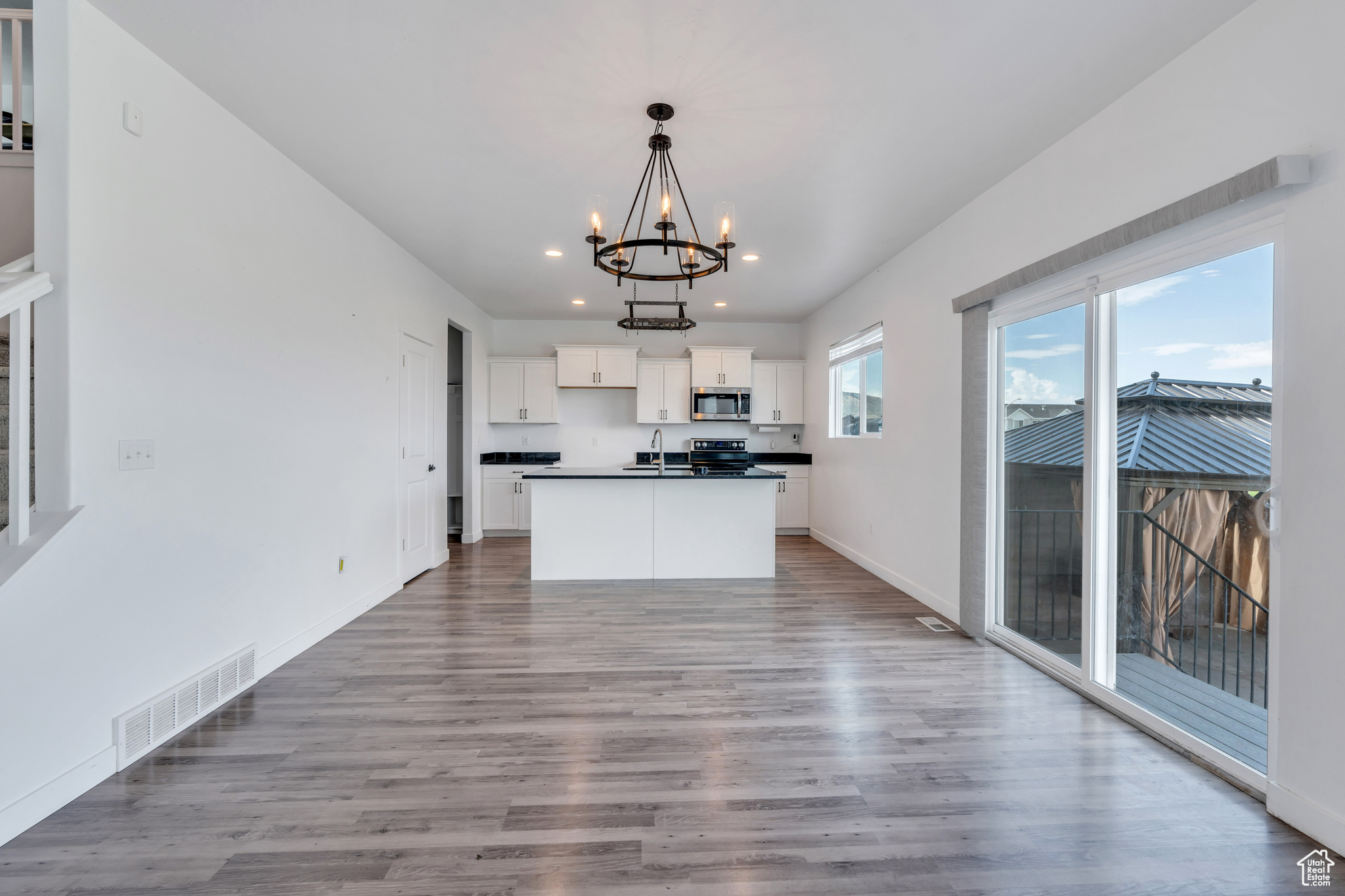 Kitchen featuring white cabinets, hanging light fixtures, light hardwood / wood-style flooring, and range with electric stovetop