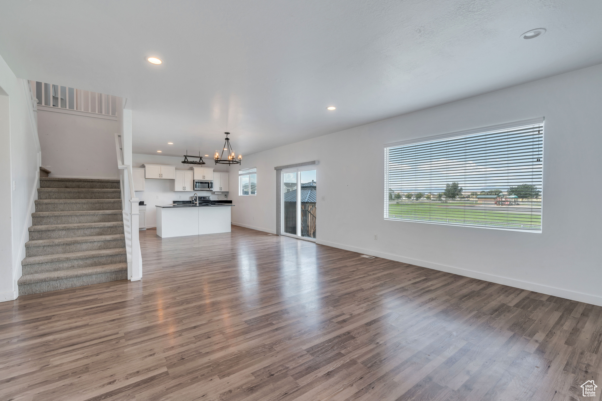 Unfurnished living room featuring plenty of natural light, a chandelier, and wood-type flooring