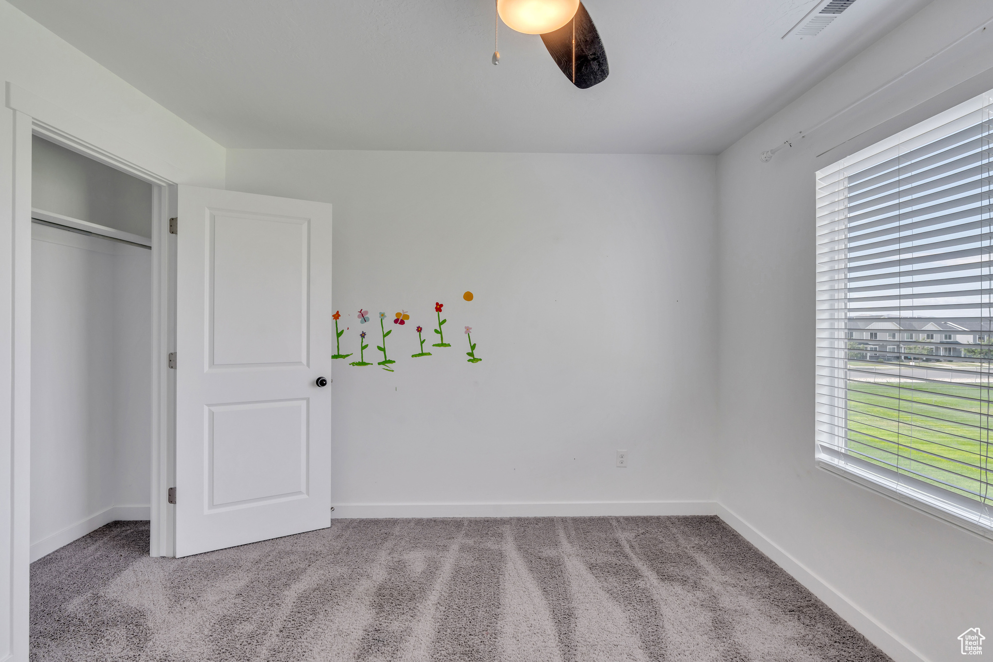 Unfurnished bedroom featuring light colored carpet, a closet, and ceiling fan