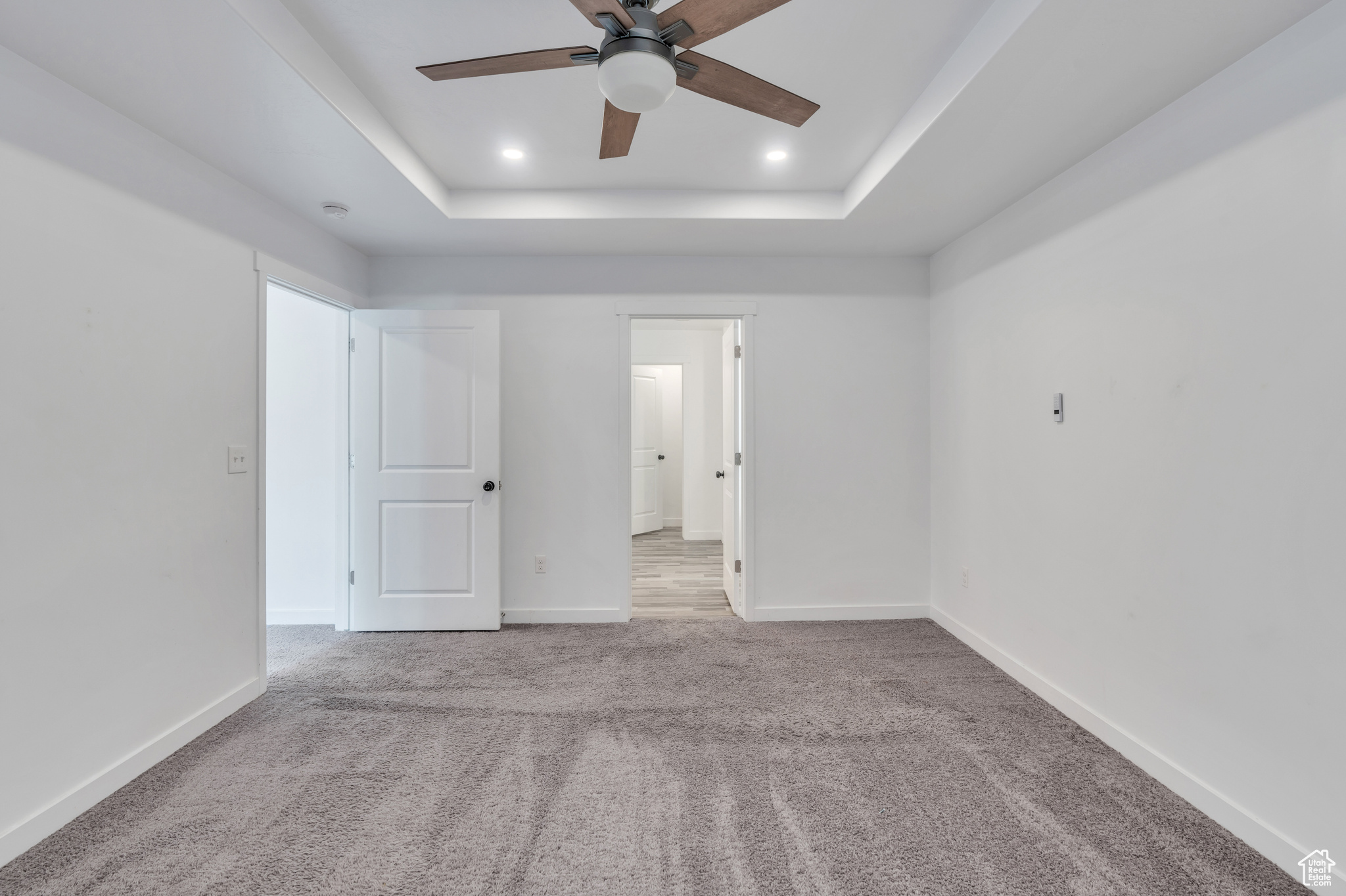 Unfurnished room with a tray ceiling, carpet floors, and ceiling fan