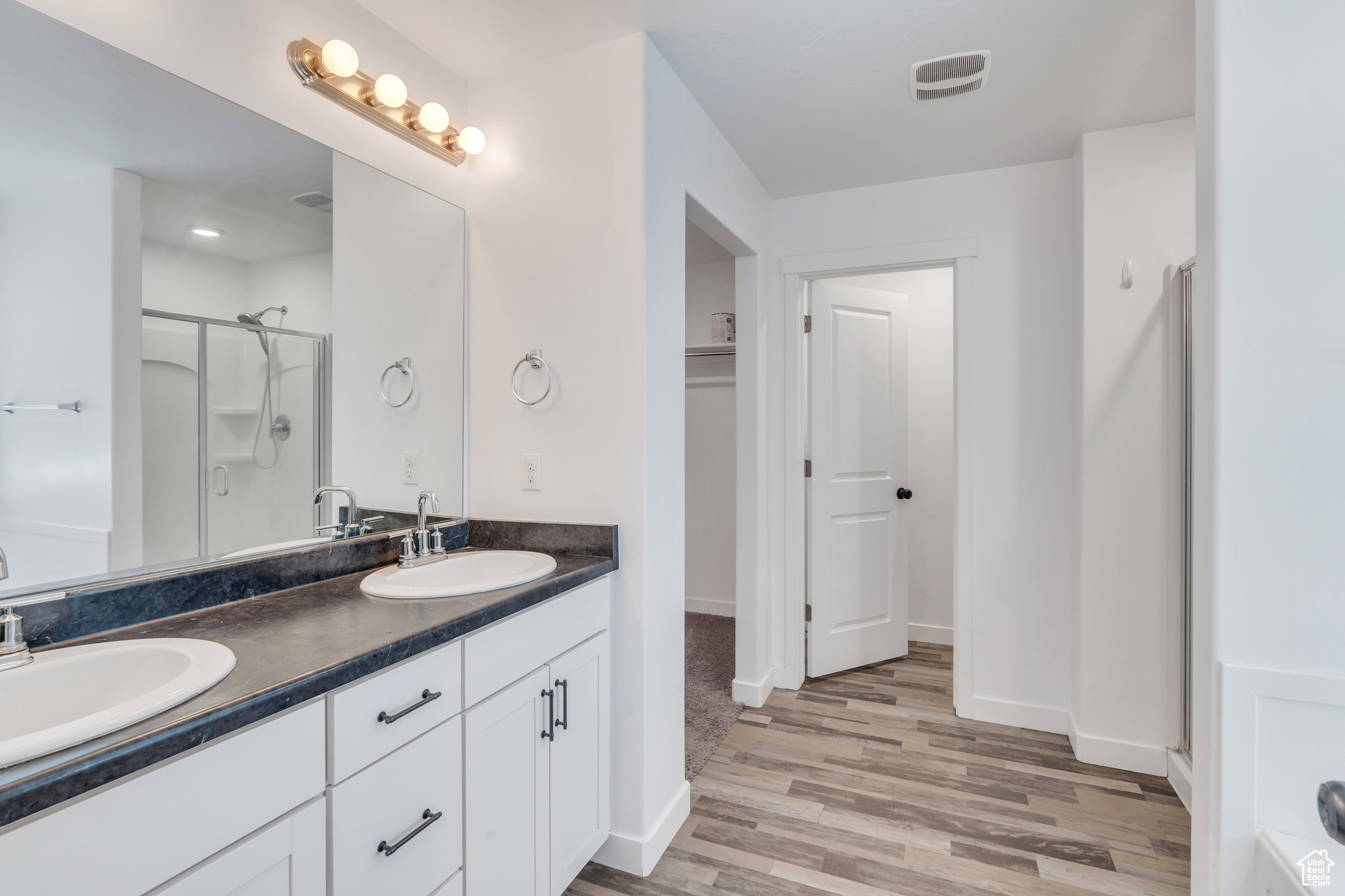 Bathroom with an enclosed shower, hardwood / wood-style flooring, and double sink vanity