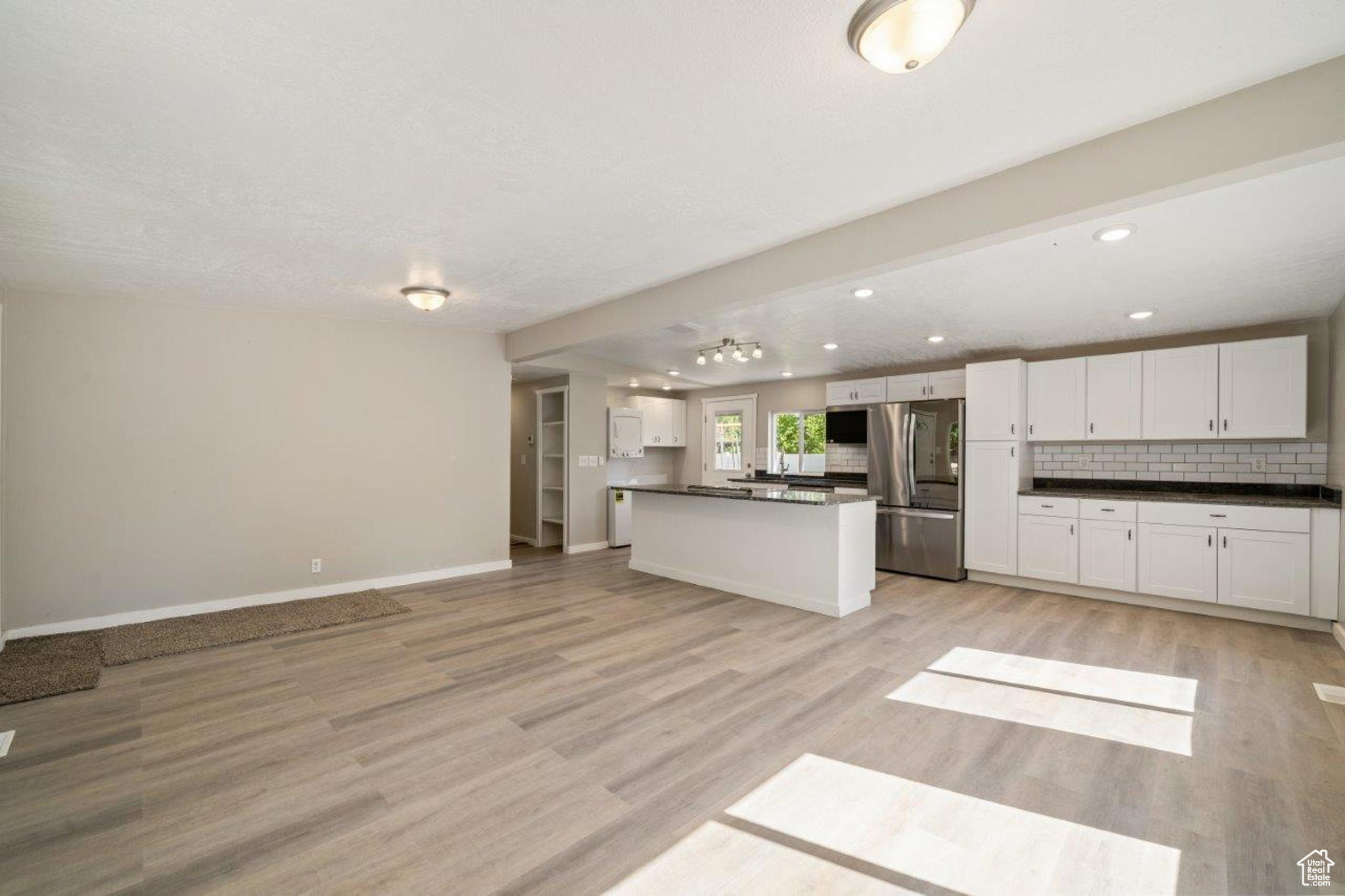 Kitchen featuring backsplash, stainless steel appliances, light hardwood / wood-style flooring, and white cabinets