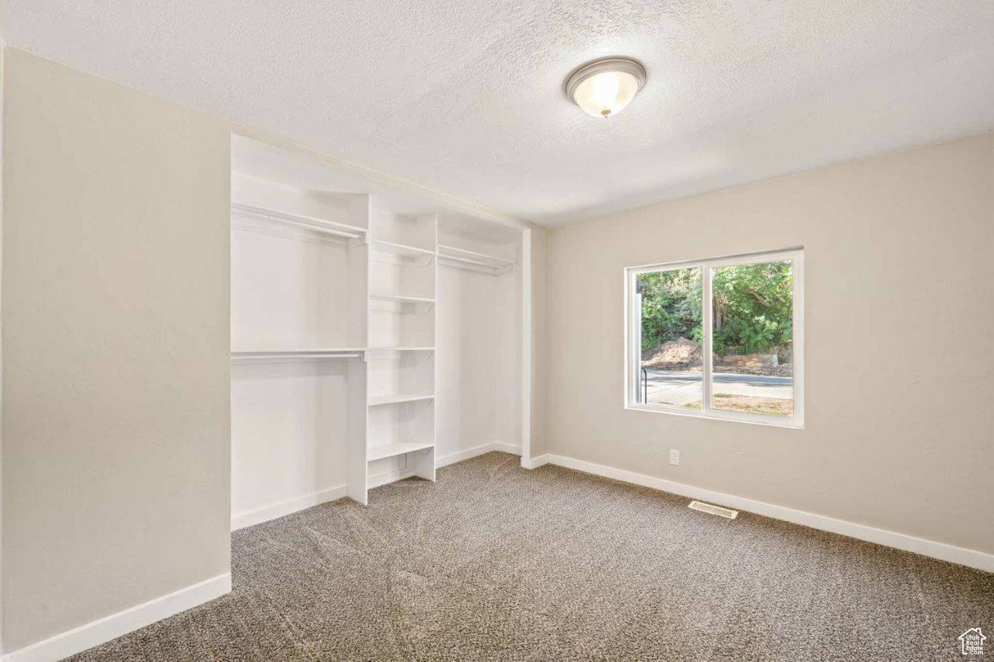 Unfurnished bedroom with carpet, a closet, and a textured ceiling