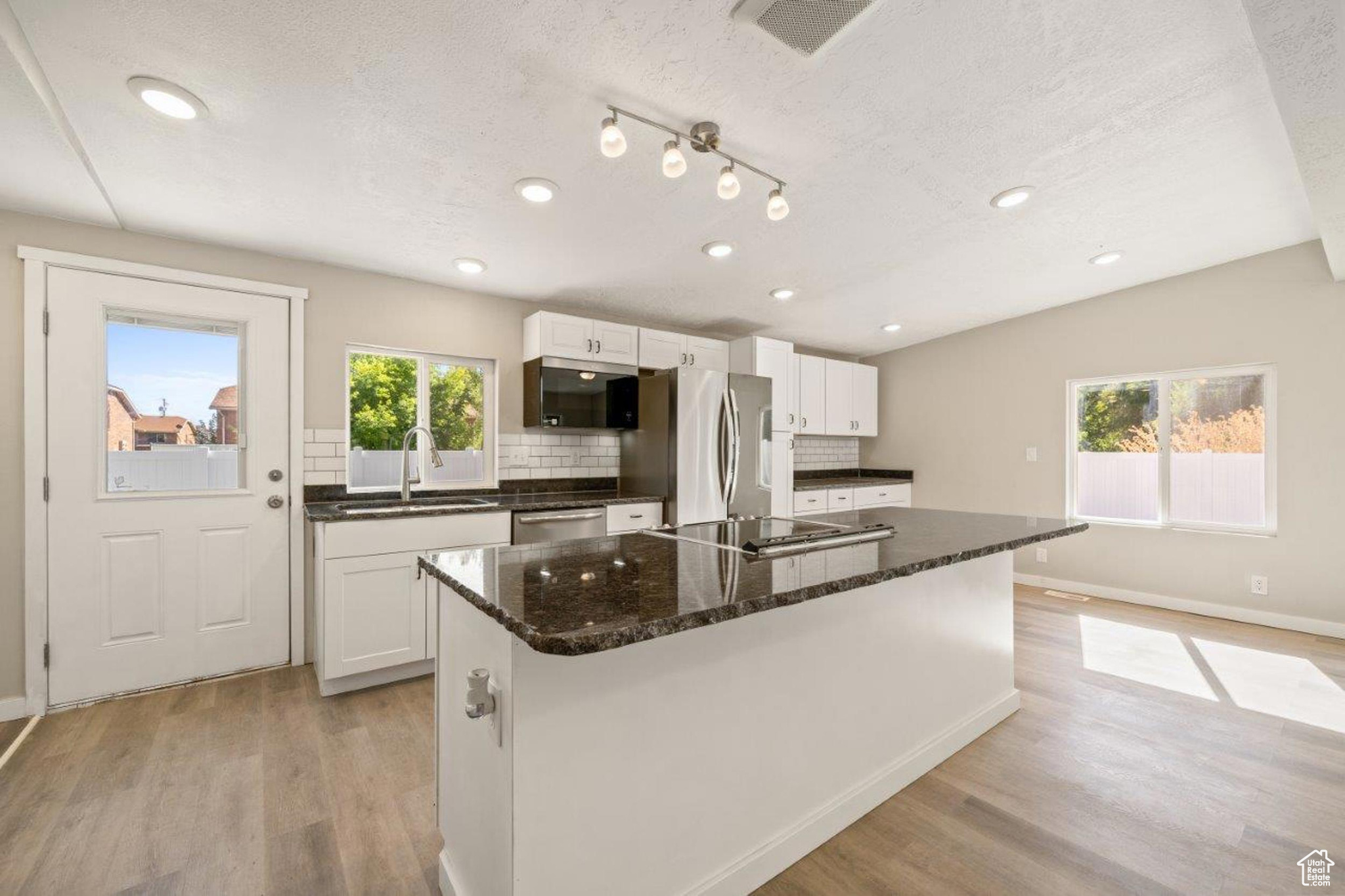 Kitchen with white cabinetry, light hardwood / wood-style flooring, stainless steel appliances, and plenty of natural light