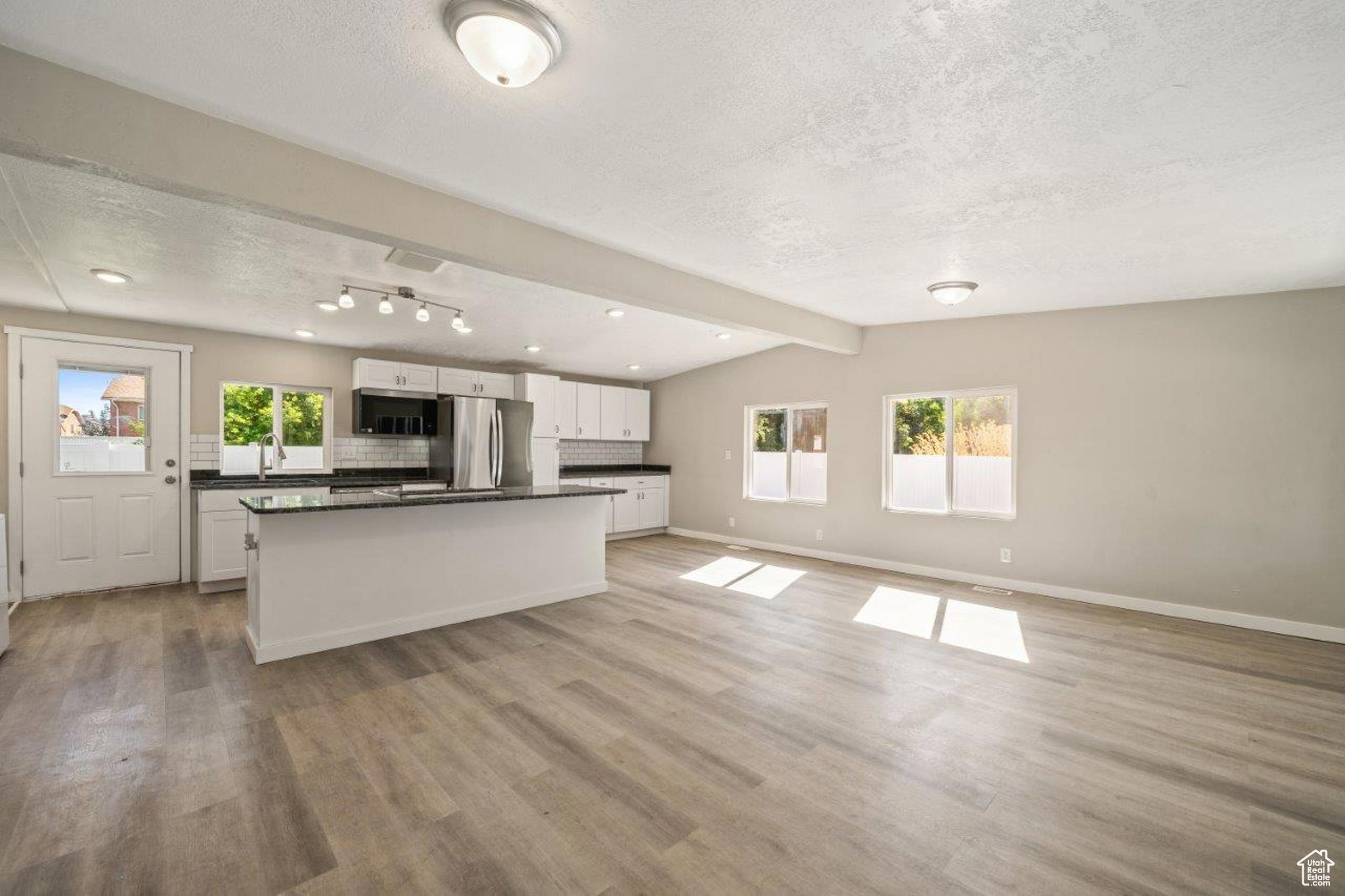 Kitchen with stainless steel appliances, light hardwood / wood-style floors, white cabinets, and a healthy amount of sunlight