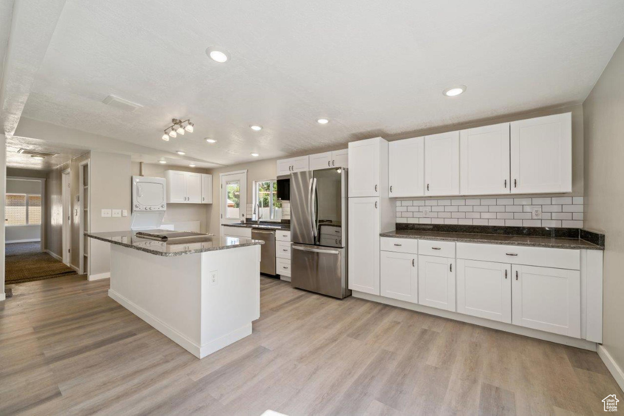 Kitchen featuring white cabinetry, light hardwood / wood-style flooring, appliances with stainless steel finishes, and a kitchen island